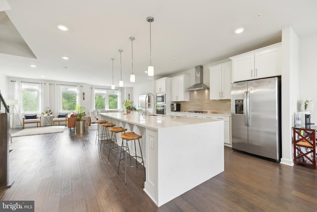 1702 River Sandstone Ter SE, Leesburg, VA 20175 - kitchen featuring stainless steel appliances, wall chimney exhaust hood, light countertops, a large island with sink, and white cabinets