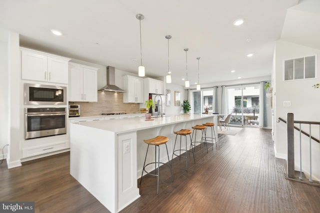 1702 River Sandstone Ter SE, Leesburg, VA 20175 - kitchen featuring appliances with stainless steel finishes, wall chimney range hood, light countertops, a spacious island, and white cabinets
