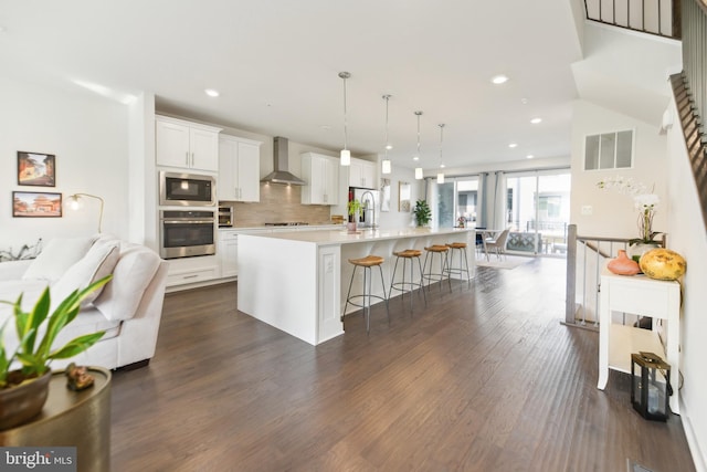 1702 River Sandstone Ter SE, Leesburg, VA 20175 - kitchen with appliances with stainless steel finishes, wall chimney exhaust hood, a breakfast bar, dark wood-style flooring, and open floor plan