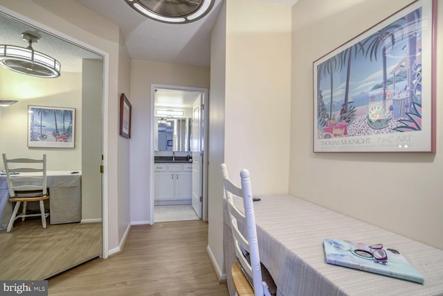 bedroom with baseboards, light wood-type flooring, and connected bathroom