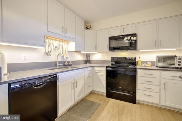 kitchen with a toaster, light wood-style floors, white cabinetry, a sink, and black appliances