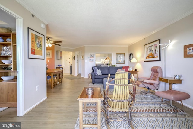 living room with baseboards, ornamental molding, light wood finished floors, and ceiling fan