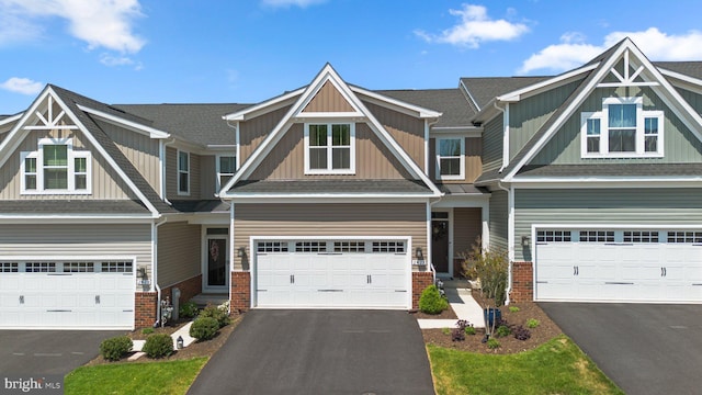 craftsman-style home featuring board and batten siding, an attached garage, aphalt driveway, and brick siding