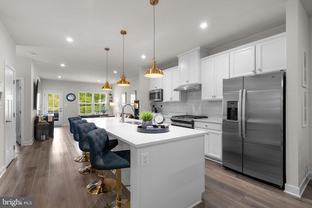 kitchen featuring a kitchen island with sink, light countertops, white cabinetry, under cabinet range hood, and appliances with stainless steel finishes