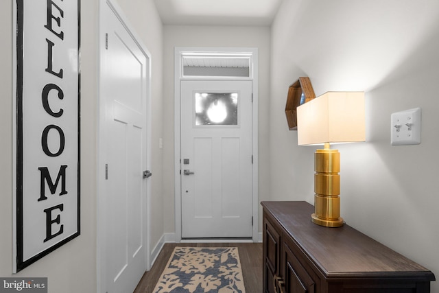 doorway to outside featuring dark wood-style flooring and baseboards