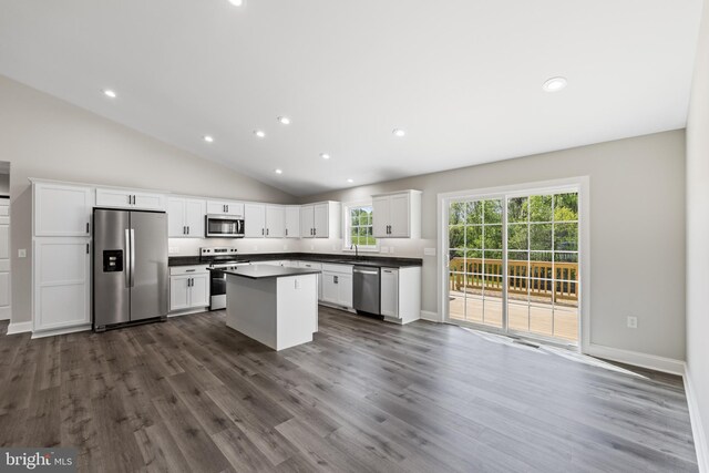 kitchen with dark wood finished floors, appliances with stainless steel finishes, white cabinets, dark countertops, and lofted ceiling