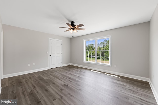 spare room with ceiling fan, baseboards, and dark wood-type flooring
