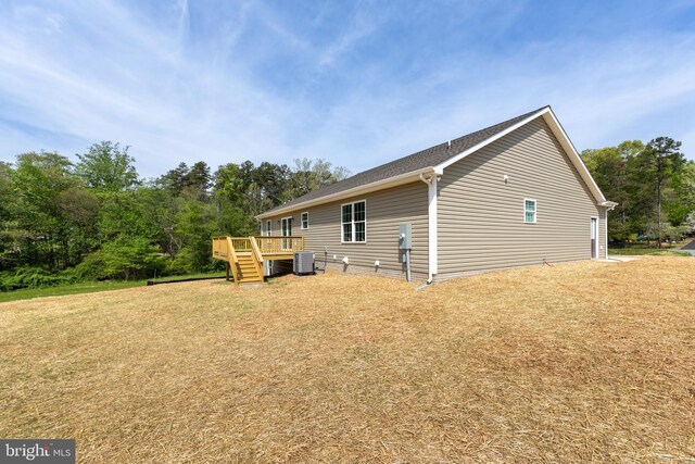view of side of home with a wooden deck, central AC unit, a yard, and stairs