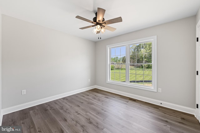 unfurnished room with a ceiling fan, visible vents, dark wood-style flooring, and baseboards