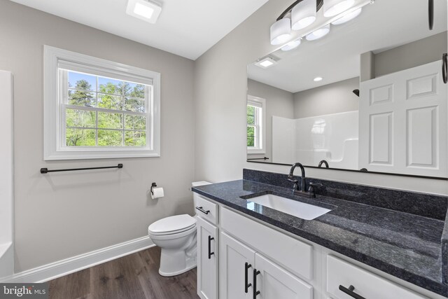 full bath featuring baseboards, walk in shower, toilet, wood finished floors, and vanity