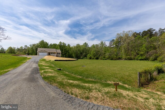 view of front of home featuring a wooded view, a front yard, a garage, and aphalt driveway