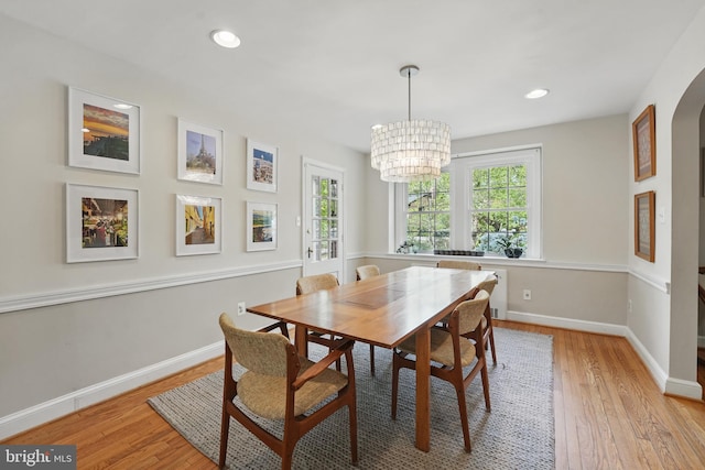 dining space featuring a chandelier, arched walkways, baseboards, recessed lighting, and light wood finished floors