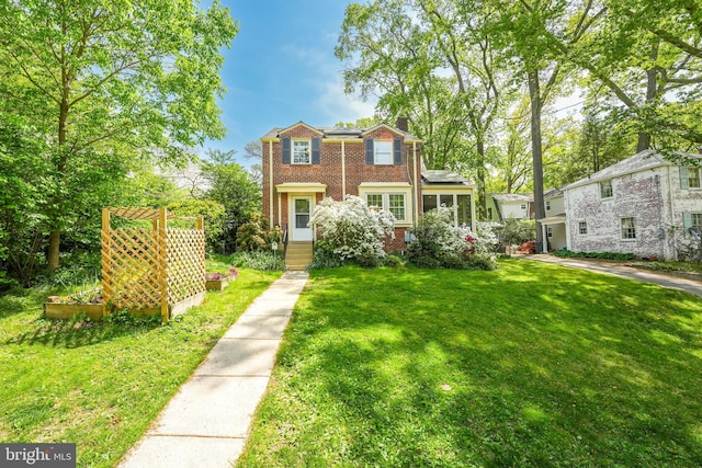 view of front of property featuring a front yard, a chimney, and brick siding