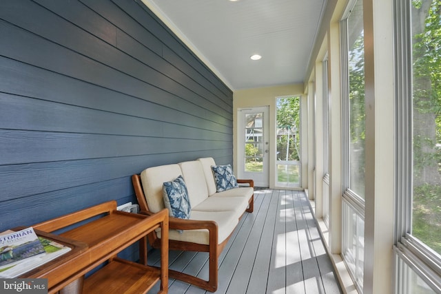 sunroom featuring wood walls and wood-type flooring
