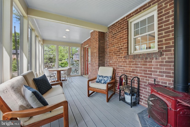 sunroom / solarium with a wood stove, hardwood / wood-style flooring, and brick wall