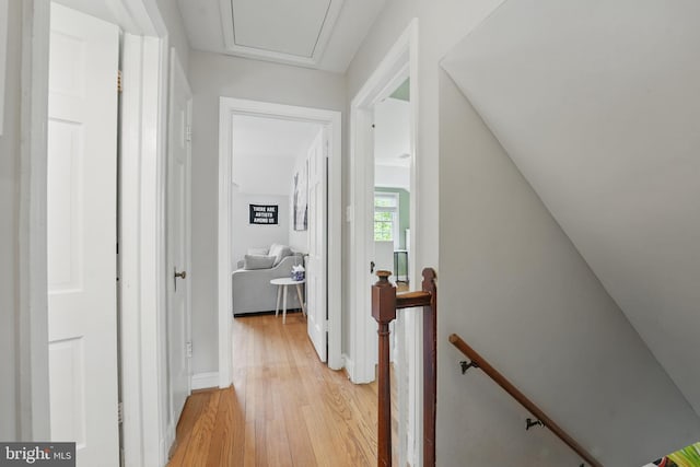 corridor with light wood finished floors and an upstairs landing