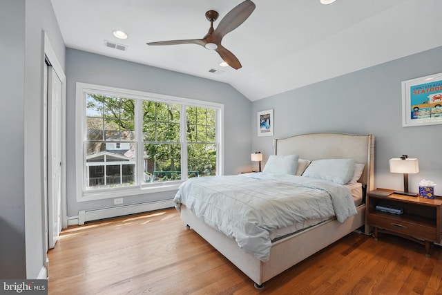 bedroom featuring baseboard heating, visible vents, wood finished floors, and lofted ceiling