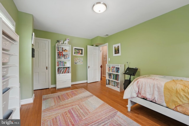 bedroom featuring baseboards, visible vents, and wood finished floors
