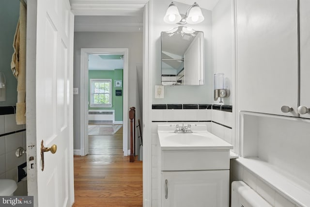 bathroom with radiator, vanity, tile walls, and wood finished floors
