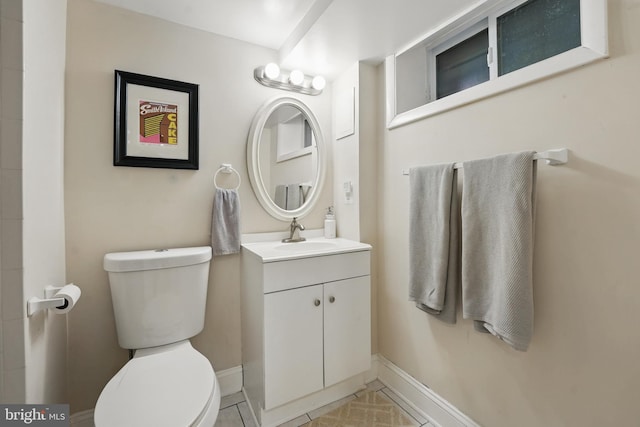 bathroom featuring toilet, tile patterned flooring, vanity, and baseboards