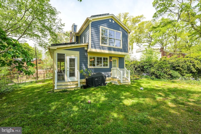 rear view of property with a chimney, fence, and a yard