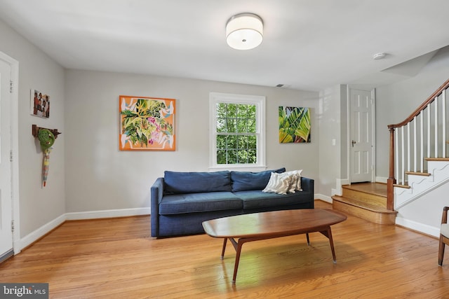 living area with stairway, light wood-type flooring, and baseboards