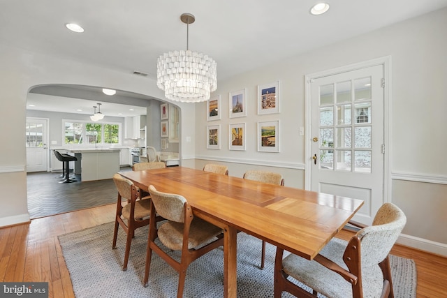 dining room featuring recessed lighting, arched walkways, baseboards, and light wood-style floors