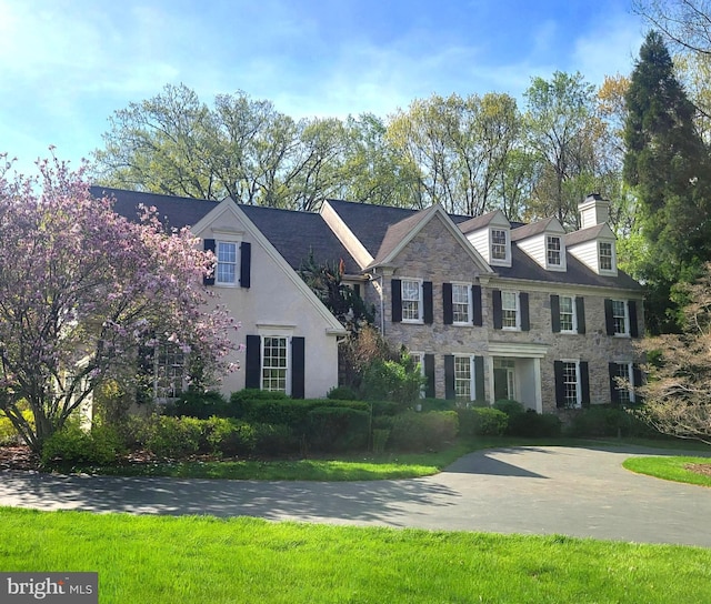 view of front of home featuring a chimney and stone siding
