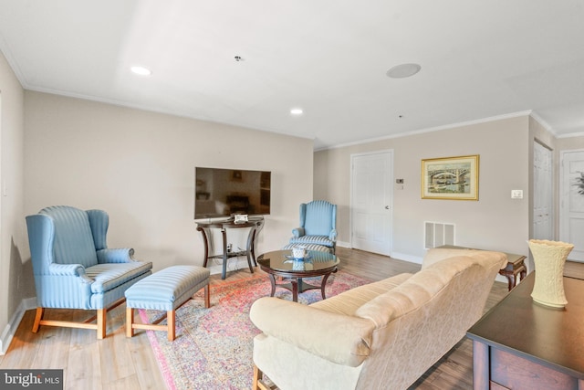 living room featuring ornamental molding, visible vents, wood finished floors, and baseboards