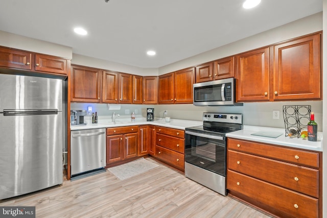 kitchen featuring appliances with stainless steel finishes, light countertops, light wood-style flooring, and a sink