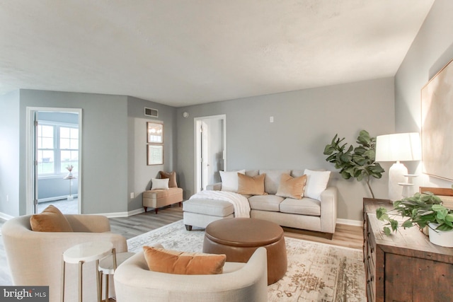 living area with baseboards, visible vents, and light wood-style flooring
