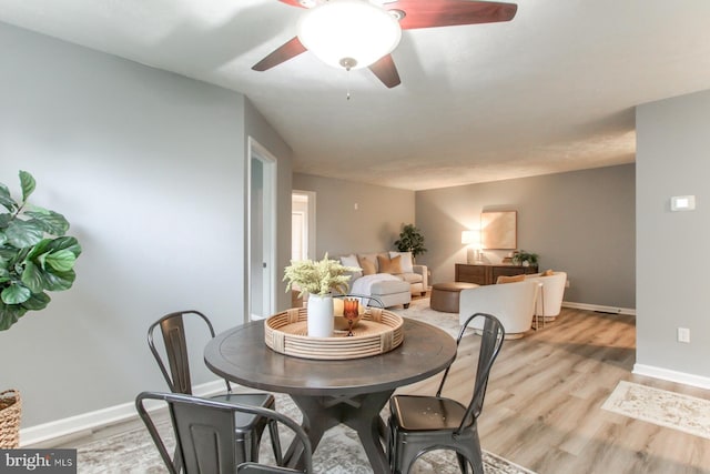 dining space featuring baseboards, ceiling fan, and light wood-style flooring
