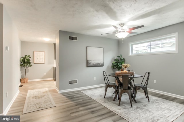 dining area with baseboards, visible vents, wood finished floors, and a ceiling fan