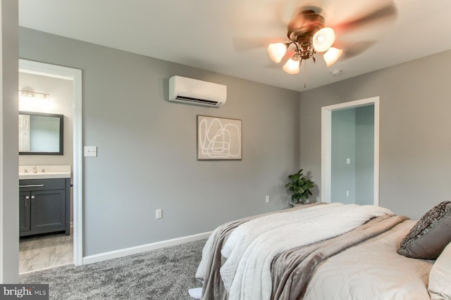 bedroom with connected bathroom, a sink, baseboards, light carpet, and a wall mounted air conditioner