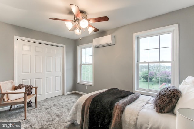 bedroom featuring a wall unit AC, a closet, baseboards, carpet, and a ceiling fan