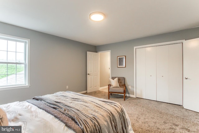 carpeted bedroom featuring baseboards and a closet