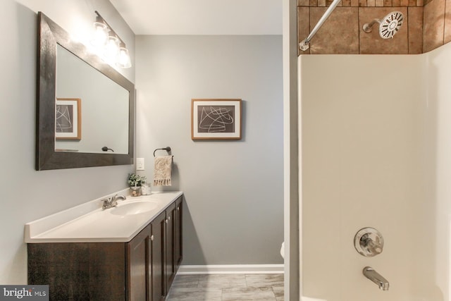 bathroom featuring baseboards, marble finish floor, shower / bathing tub combination, and vanity
