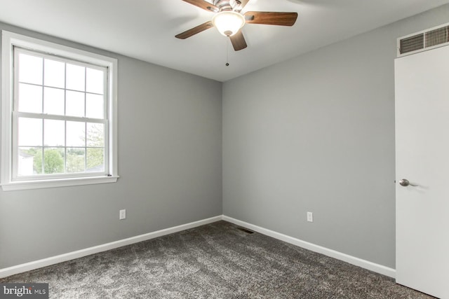 spare room with baseboards, visible vents, dark carpet, and ceiling fan