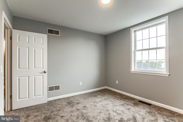 carpeted spare room featuring visible vents and baseboards