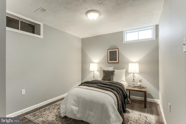bedroom featuring baseboards, visible vents, and wood finished floors