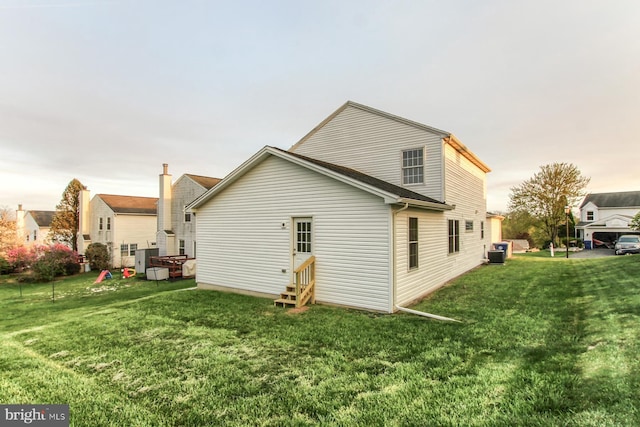 rear view of house featuring a lawn, central AC, and entry steps