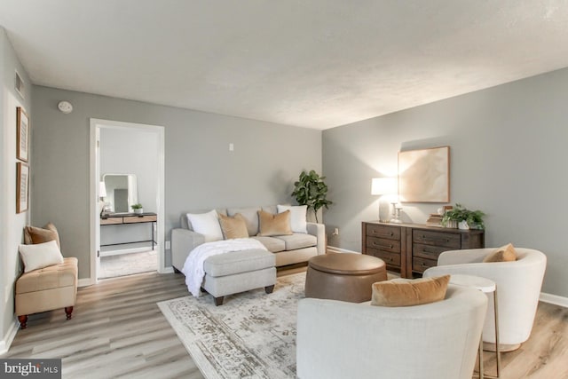 living area featuring baseboards, visible vents, and light wood-style flooring