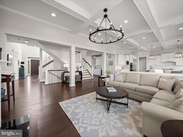 living room with coffered ceiling, stairs, beam ceiling, and a notable chandelier