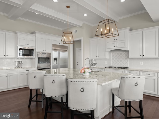 kitchen featuring an inviting chandelier, built in appliances, beamed ceiling, and white cabinetry