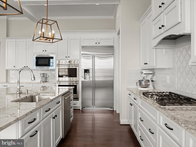 kitchen featuring a sink, built in appliances, decorative backsplash, and white cabinetry