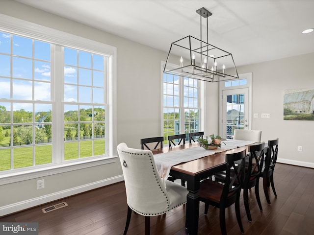 dining area featuring visible vents, a wealth of natural light, baseboards, dark wood-type flooring, and a notable chandelier
