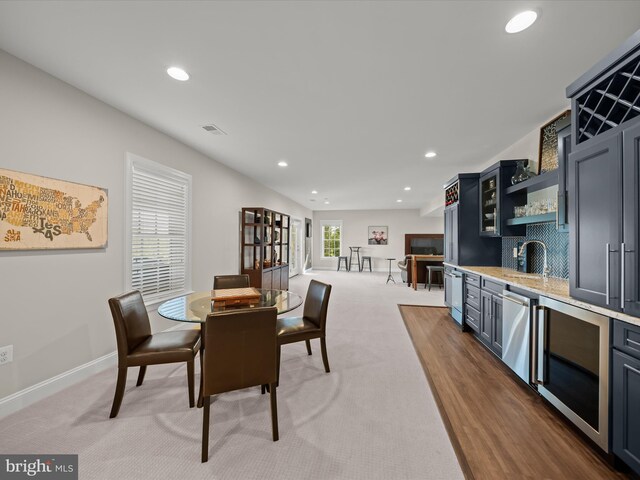 carpeted dining area with a sink, recessed lighting, wet bar, and visible vents