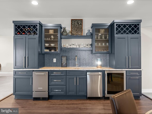 bar with tasteful backsplash, a sink, beverage cooler, wet bar, and dark wood-type flooring