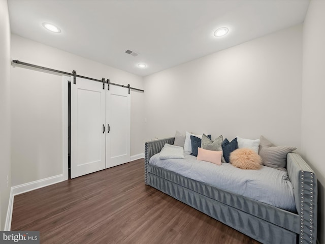 bedroom featuring visible vents, wood finished floors, baseboards, recessed lighting, and a barn door
