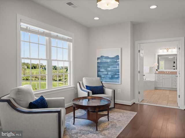 sitting room with baseboards, a wealth of natural light, wood finished floors, and visible vents